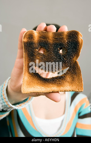 Frau mit verbranntem Toast vor Gesicht Stockfoto