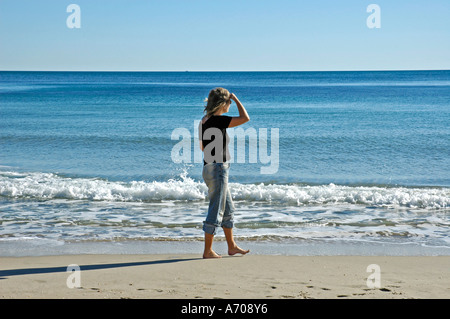 Junge Frau in Jeans sieht in der Ferne am Strand. 30-40-45 Jahre, Mittelmeer, Costa Blance, Spanien Stockfoto