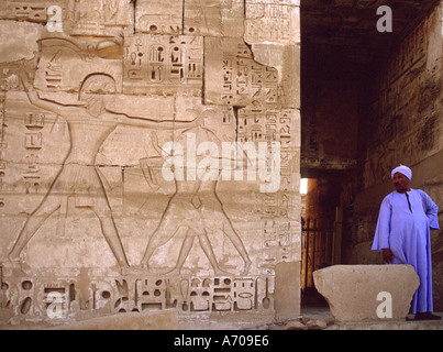 Im Madinat Habu schaut ein ägyptischen Führer eine Schnitzerei von Ramses III, seine Feinde zu besiegen Stockfoto