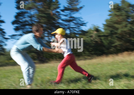 Sechs Jahre alter Junge läuft mit ausgestreckten Armen in den Armen seiner Mutter Stockfoto