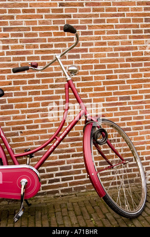 Typisch holländisches Fahrrad parkte vor einem roten Backsteinhaus in Haarlem, Nordholland. Klassisches, kastanienbraunes Vintage-Fahrrad auf einem Bürgersteig. Stockfoto