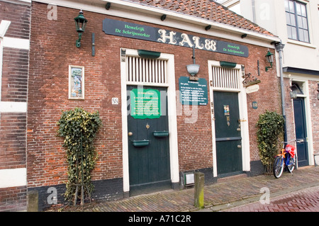 Historisches Hal88-Gebäude in Haarlem, Nordholland. Traditionelle Ziegelfassade mit grünen Türen, holländischen Schildern und einem Fahrrad, das auf dem Bürgersteig geparkt ist. Stockfoto