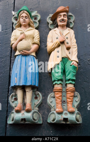 Mann und Frau Bass Relief auf Hal88 Gebäude in Haarlem, Nordholland. Traditionelle Holzfiguren eines Paares an einer dunklen Türfassade. Stockfoto