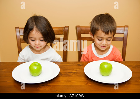 Jungen und Mädchen am Tisch mit Äpfeln auf Platten Stockfoto