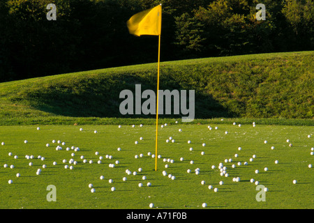 Resultate von weißen Golfbälle auf einem Golfplatz Grün eine gelbe Flagge auf einem gelben Pfosten markiert das Loch Stockfoto