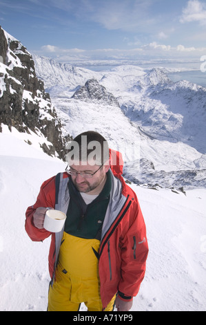 Bergsteiger auf dem Gipfel des Bruach Na Frithe, hält für einen Kaffee, Cuillin Ridge, Isle Of Skye, Schottland, Vereinigtes Königreich, unter winterlichen Bedingungen Stockfoto