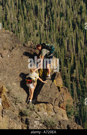 Mann und Frau paar Wandern auf einem felsigen Hügel Seite Gelände hoch über den Baumwipfeln in Idaho Stockfoto