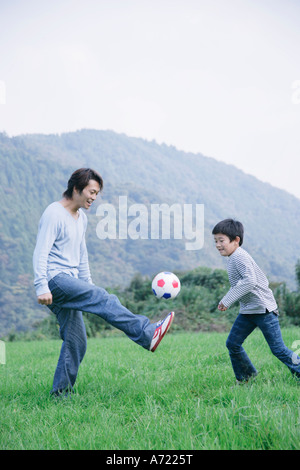 Vater und Sohn spielt Fußball auf Wiese Stockfoto