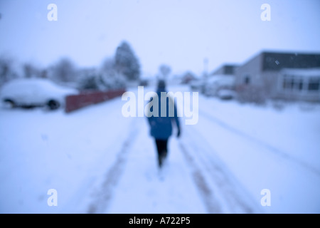 Einsame Frau zu Fuß auf einer schneebedeckten Straße umgeben von Häusern Inverness Schottland Stockfoto