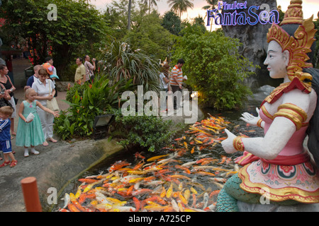 Kleine Mädchen füttern Fische am Eingang zum Phuket FantaSea, einem kulturellen Freizeitpark auf der Insel Phuket, Thailand. Stockfoto