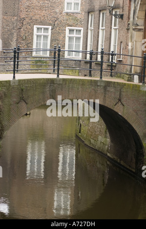 Kleine Ziegelbogenbrücke über einen Wasserkanaltunnel mit Reflexionen von Gebäuden in den Bosch, Holland. Stockfoto