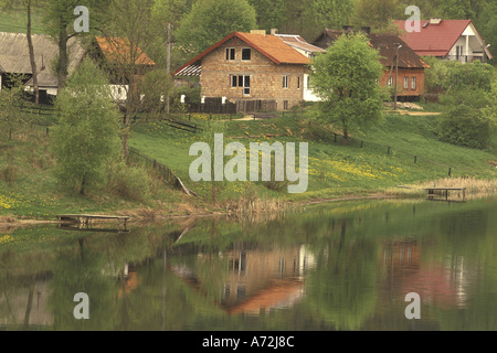 Europa, Polen, Ermland und Masuren, Rapaty Dorfhäuser und Stream im Frühling Stockfoto