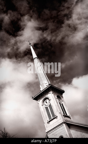 alten Uhrturm mit Wetterhahn auf dem Kirchturm in Sepia-Tönen auf der Suche nach oben gegen einen dunklen Gewitterhimmel Stockfoto