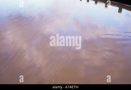 Detail der Strand mit seichtem Wasser streaming über Sand und gold und grauen Wolken und blass blauen Himmel mit Buhne widerspiegelt Stockfoto