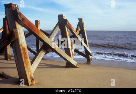 Verwittert und Rost – gebeizt bleibt der schwere Holz stützen für Pier oder Steg am Sandstrand mit grauen Meer und milchig blauen Himmel Stockfoto