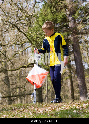 Kleiner Junge Stanzen einen Kontrollpunkt mit seiner e-Karte-Tag bei einem Orientierungslauf-Event Forest of Dean England UK Stockfoto