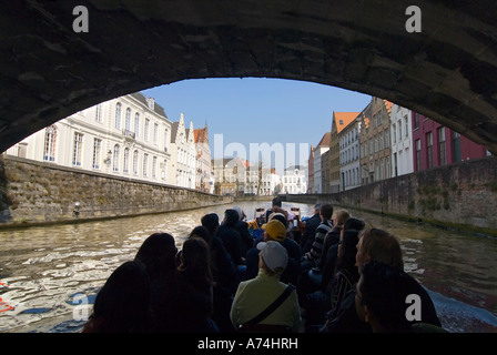 Horizontale Ansicht von Touristen unter einer Brücke auf eine geführte Bootsfahrt durch die Kanäle von Brügge an einem sonnigen Tag Stockfoto
