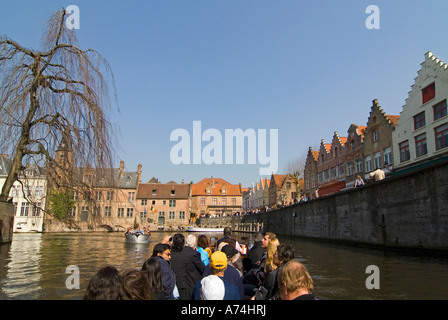 Horizontale Ansicht von Touristen genießen eine geführte Bootsfahrt durch die Kanäle von Brügge an einem sonnigen Tag. Stockfoto