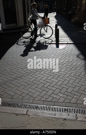 Stark zurück beleuchteten Bild einer Frau mit einem altmodischen Fahrrad mit Fahrradkorb Stockfoto