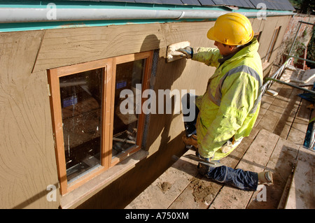 EIN GIPSER RENDERING UM NEUE HARTHOLZ FLÜGELFENSTER AUF EINER HÜTTE UNTER RENOVIERUNG UK Stockfoto