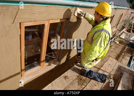 EIN GIPSER RENDERING UM NEUE HARTHOLZ FLÜGELFENSTER AUF EINER HÜTTE UNTER RENOVIERUNG UK Stockfoto