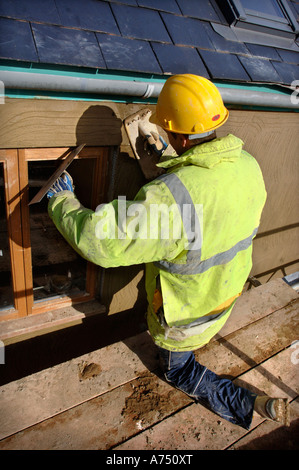 EIN GIPSER RENDERING UM NEUE HARTHOLZ FLÜGELFENSTER AUF EINER HÜTTE UNTER RENOVIERUNG UK Stockfoto