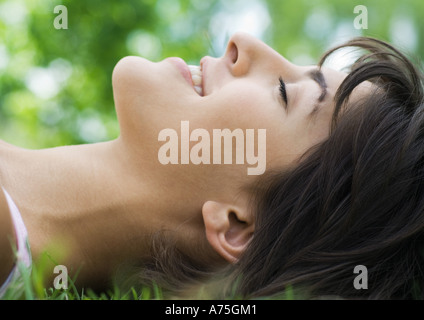 Junge Frau mit geschlossenen Augen im Grass liegen Stockfoto