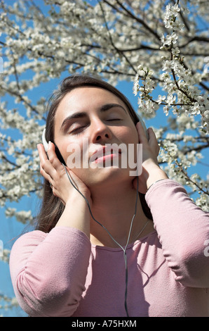 Junge Frau trägt Kopfhörer blühen im Frühjahr Hintergrund Stockfoto