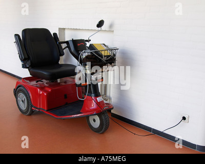 Elektro-Scooter für Senioren laden nach Gebrauch Steckdose eingesteckt Stockfoto