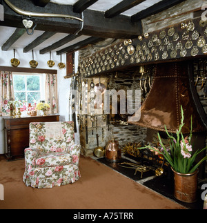 Ferienhaus Wohn-Esszimmer mit Blumendruck Sessel neben Inglenook Kamin mit Pferd Messing auf großen Balken Stockfoto