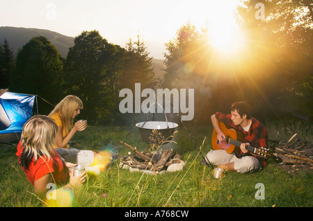 Junge Menschen haben Picknick, Mann spielt Gitarre Stockfoto