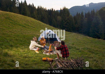 Drei junge Leute sitzen am Lagerfeuer Stockfoto