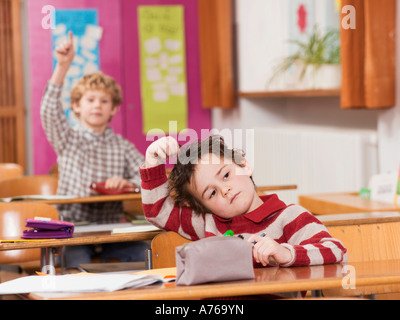 Kinder (4-7) im Klassenzimmer, Fokus auf junge mit hand im Haar im Vordergrund Stockfoto