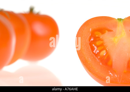 Ein Teil der drei ganze Tomaten und eine Hälfte auf einem reinen weißen Hintergrund. Stockfoto
