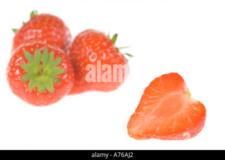 Drei ganze Erdbeeren und eine halbieren auf einem reinen weißen Hintergrund. Stockfoto