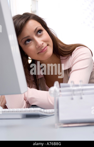 Junge Frau am Computer im Büro sitzen, nachschlagen, Lächeln Stockfoto