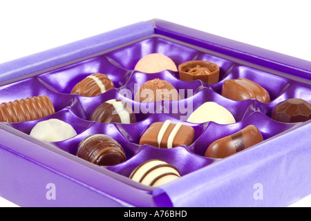 Auswahl an Pralinen in lila Tablett auf einem reinen weißen Hintergrund. Stockfoto