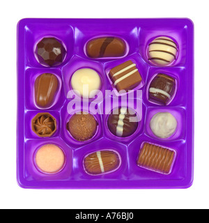 Draufsicht auf eine Auswahl an Pralinen in lila Schale auf einem reinen weißen Hintergrund. Stockfoto