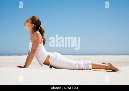 Junge Frau, die Ausübung von Yoga am Strand, Seitenansicht Stockfoto