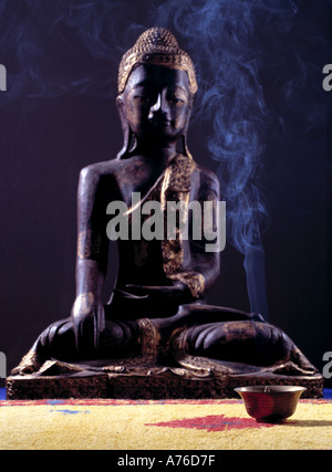 Hölzernes Schnitzen von Buddha vor Rauchen Weihrauch Stockfoto