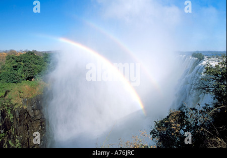 Zwei Regenbögen vor einem blauen Himmel über Victoria Falls aufgrund der großen Menge von Spray in der Luft bilden. Stockfoto