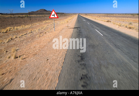 Weitwinkelaufnahme aus einer trostlosen gerade leere Straße und eine einsame Straße Verkehr Wegweiser in der Wüste von Namibia mit Motion blur. Stockfoto