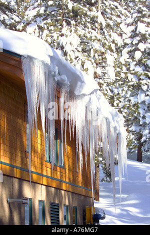 Eiszapfen hängen von der Dachterrasse des Gebäudes/Holzhaus. Stockfoto