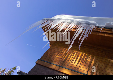 Eiszapfen hängen von der Dachterrasse des Gebäudes/Holzhaus. Stockfoto