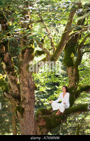 Junge Frau, meditieren auf Ast, Seitenansicht Stockfoto