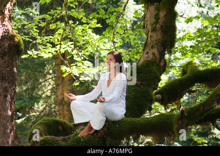 Junge Frau, meditieren auf Ast, Seitenansicht Stockfoto