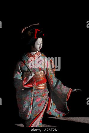 Geschnitzte japanische Puppe gekleidet in Seide Kimono Set vor einem schwarzen Hintergrund Antiquitätengeschäft Kyoto Japan Stockfoto