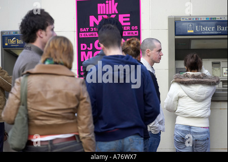 Menschen, die Warteschlangen an einem Geldautomaten ATM während Sie Weihnachts-shopping in Belfast-Heiligabend-Nordirland Stockfoto