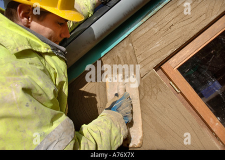 EIN GIPSER RENDERING UM NEUE HARTHOLZ FLÜGELFENSTER AUF EINER HÜTTE UNTER RENOVIERUNG UK Stockfoto