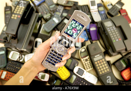 Die Geschichte des Handys angezeigt mit Modellen aus den 1980er Jahren auf 3 Bildtelefone. Die Hand einer Frau hält ein Clamshell-Modell geöffnet Stockfoto